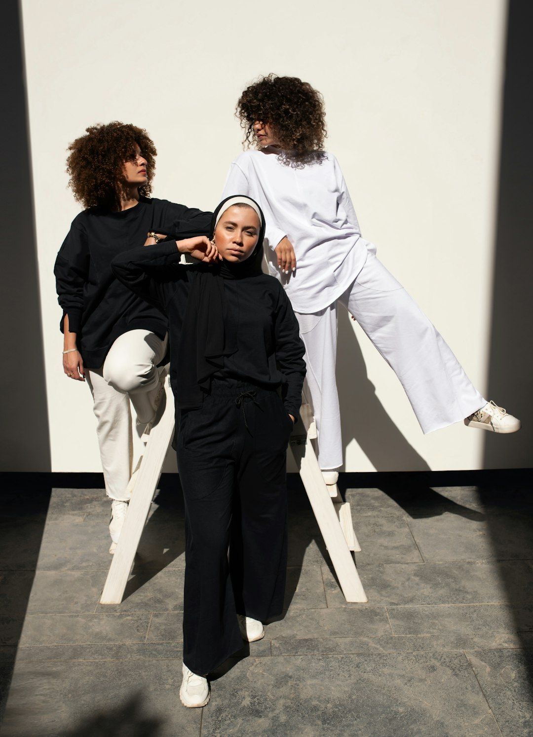 man in black long sleeve shirt and white pants standing beside woman in white